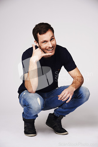 Image of Man, portrait and call me hand sign of a person with flirty and emoji gesture in studio. Isolated, grey background and male model with a smile and happiness from flirt and casual fashion alone