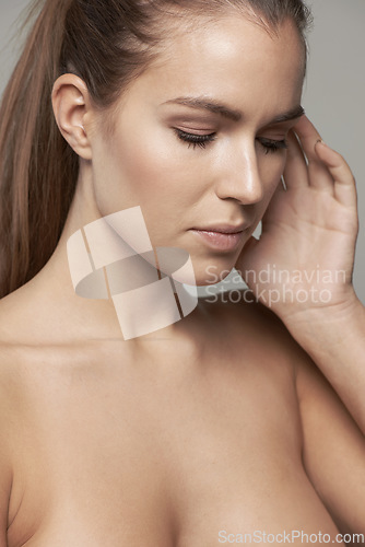 Image of Touch, beauty and serious face of woman in studio for wellness, facial treatment and self care. Skincare, salon and female person with natural glowing skin, makeup and cosmetics on gray background