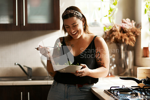 Image of Woman, diet and person eating salad in her home kitchen and is happy for a meal with nutrition or healthy lunch. Smile, food and young female vegan in her apartment or house and eat vegetables