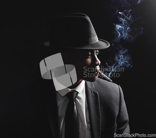 Image of Man, gangster and cigarette in studio by dark background with smoke, silhouette and dangerous in shadow. Mafia, secret agent or male in night for smoking with vintage aesthetic by black backdrop