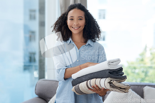 Image of Portrait, laundry and cleaning with a black woman in her home, holding fresh towels during housework. Smile, fabric and washing with a happy young female cleaner in the living room of her apartment