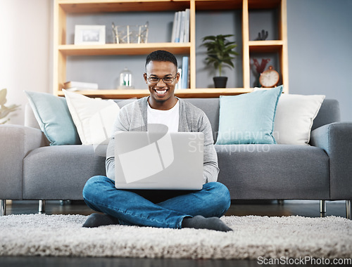 Image of Computer, floor and portrait of man in home, online research and typing in living room for work or career opportunity. Happy, carpet and young african person working on laptop or technology in lounge