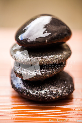 Image of Stones, zen and wet rocks for hot stone massage at a spa for luxury and wellness. Peace, closeup and rock balance with tranquility and feng shui for meditation, holistic therapy and water on pile