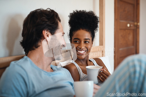 Image of Happy interracial couple, bed and coffee in relax for morning, bonding or breakfast at home. Man and woman smiling for tea, conversation or talk on relaxing weekend or holiday together in the bedroom