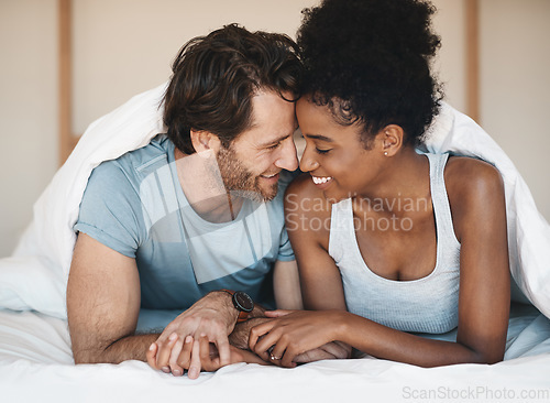 Image of Happy interracial couple, bed and intimate morning in relax or bonding relationship at home. Man and woman smiling in joyful happiness for love, affection or relaxing weekend together in the bedroom