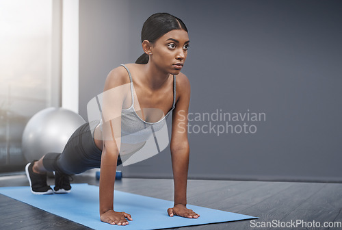 Image of Stretching, training and woman in the gym for fitness, exercise or workout for commitment to health and wellness. Yoga, serious and healthy young female person ready morning sport performance