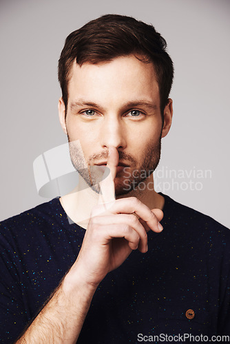 Image of Man, secret and portrait with silence, hand and finger emoji sign in a studio. Isolated, gossip and whisper of a young male model face with confidential, lips and person with privacy and stop gesture