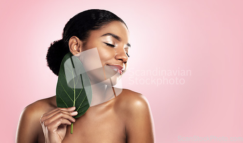 Image of Happy woman, leaf and natural beauty in studio, pink background and mockup for aesthetic cosmetics. Face, african model and skincare from plants, green leaves and sustainability of vegan dermatology