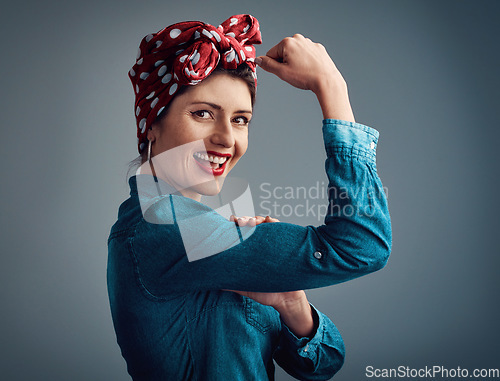 Image of Pinup girl, strong and flexing muscle portrait in studio for beauty, women power and fashion. Happy female person show bicep on a grey background for motivation, freedom and retro or vintage style