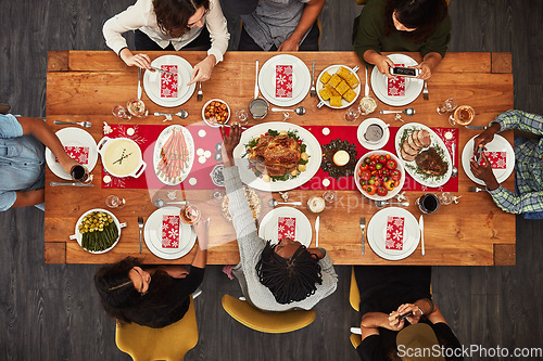 Image of Thanksgiving, overhead and friends sitting around a table for a food meal during a celebration event. Family, roast or nutrition with a man and woman group in the living room for a social gathering