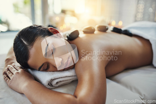 Image of Woman, relax and sleeping in rock massage for skincare, relaxation or beauty treatment on bed at spa. Female relaxing asleep with eyes closed with hot rocks on back for healthy body care at resort