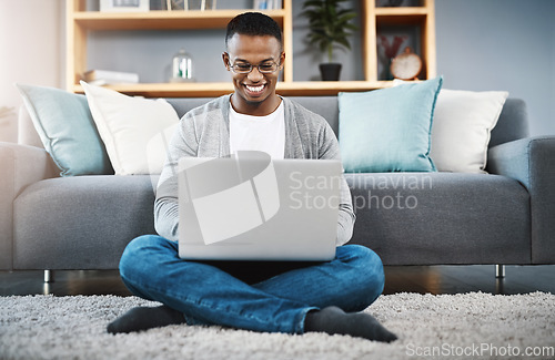 Image of Laptop, floor and happy man with work from home, online research and typing in living room for career opportunity. Relax, carpet and young african person working on computer or technology in lounge