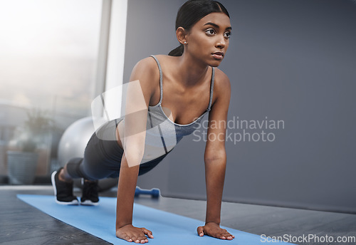 Image of Push ups, fitness and woman in the gym training, exercise or workout for commitment to health and wellness. Yoga, serious and healthy female person start stretching body for morning sport performance