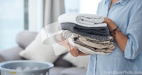 Image of Hands, laundry and spring cleaning with a woman holding a pile of fresh towels in the living room of her home. Fabric, hospitality and washing with a female cleaner in her apartment for housework