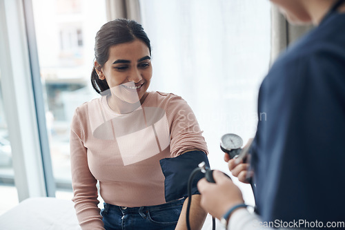 Image of Blood pressure, woman and health check with a smile at a clinic and healthcare hospital with doctor. Monitor, checking and nurse with young female patient at a wellness and medical consultation