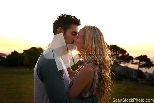 Image of Couple kissing, nature and trees in sunset with love, romance and date on adventure, travel or honeymoon. Man, woman and kiss with hug, care and outdoor for safari, travel or travel in countryside