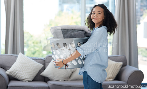 Image of Portrait, laundry and spring cleaning with a woman in the living room of her home carrying a basket. Happy, smile and housework with a young female cleaner carrying fresh washing in her apartment