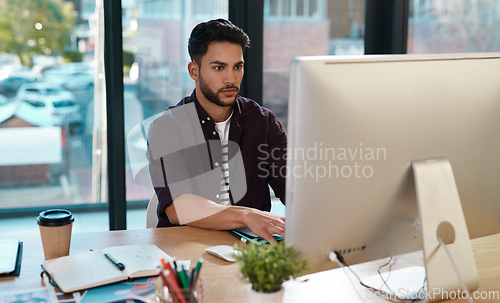 Image of Business, computer and man working at a desk while online for research or creative work. Male entrepreneur person at workplace with focus and internet connection for designer project or reading email