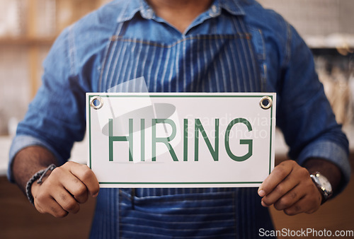 Image of Closeup, hiring sign and man advertising employment in shop, store and notice of recruitment opportunity. Hands, banner and recruiting poster for outsourcing, vacancy and job hire in small business