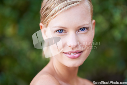 Image of Portrait, beauty and blue eyes with a woman outdoor on a green background in nature for skincare. Face, spring and smile with an attractive young female model posing outside in a natural environment