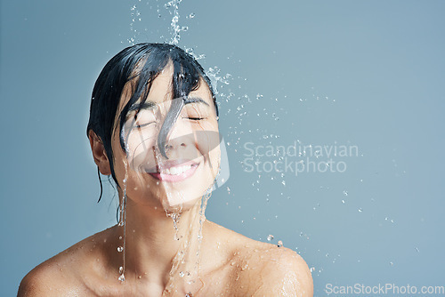 Image of Shower, beauty and face of woman with water in studio on blue background for wellness, cleaning and grooming. Skincare, bathroom and female person with splash for washing hair, body and cleansing