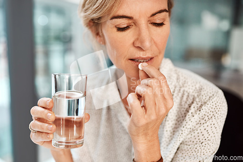 Image of Pill, water and senior woman drinking medicine or supplements for illness or health care in her office. Medical, drugs and sick elderly female person healing and drink tablet or vitamin