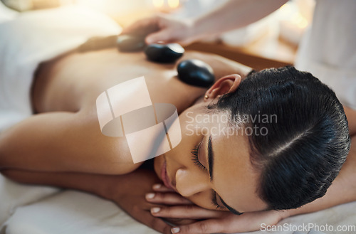 Image of Woman, relax and sleeping for back massage, skincare or relaxation at indoor beauty spa on bed. Female relaxing with hands of masseuse applying hot rocks for physical therapy or treatment at resort