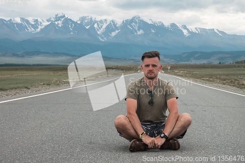 Image of man sitting on road in Altai mountain.