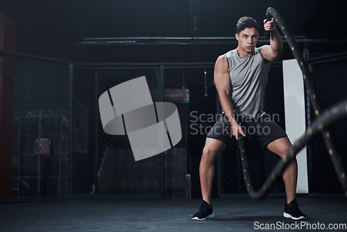 Image of Fitness, battle ropes and man at the gym doing strength, cardio and challenge workout. Strong, energy and male athlete doing exercise or training with equipment for health and wellness in sports club