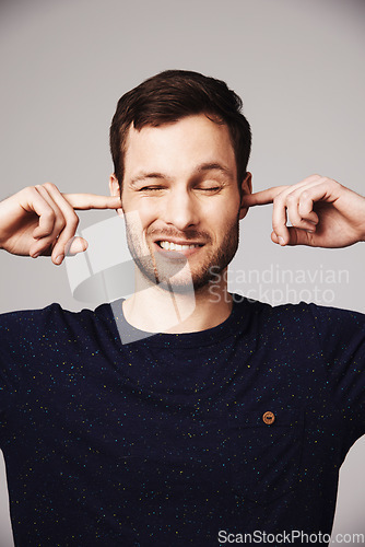 Image of Block sound, man and finger in ears of a person loud music problem in a studio. Frustrated, isolated and grey background of a male model pain with closed ear from noise for silence and peace