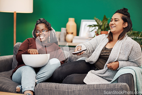 Image of Girl friends, watching tv and home living room laughing on a couch with a happy smile. Series, funny movie and women together in a lounge with a friend looking at a television in house with popcorn