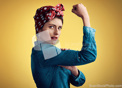 Image of Woman, strong and flexing muscle portrait of a pinup girl in studio for beauty, power and fashion. Female person show bicep on a yellow background for motivation, freedom and retro or vintage style