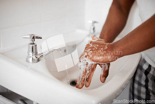 Image of Clean, hygiene and person washing hands in the bathroom with soap for wellness, health and bacteria prevention. Protection, home and man cleaning hand with water in his apartment as morning routine