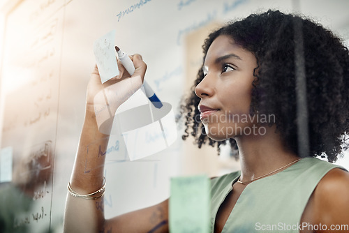 Image of Glass wall, black woman and writing, planning or strategy in office workplace. Brainstorming, board and African business person write, working on project and schedule, sticky notes or information.