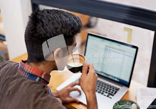 Image of Man drinking coffee while working with a laptop in a cafeteria doing research for remote work project. Technology, caffeine and male employee planning a creative report on a computer in restaurant.