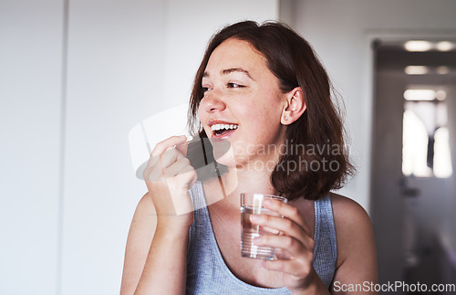 Image of Healthcare, medication and woman drinking a pill with a glass water for wellness at her home. Medicine, medical and happy female person taking a vitamin, supplement or tablet with liquid in apartment