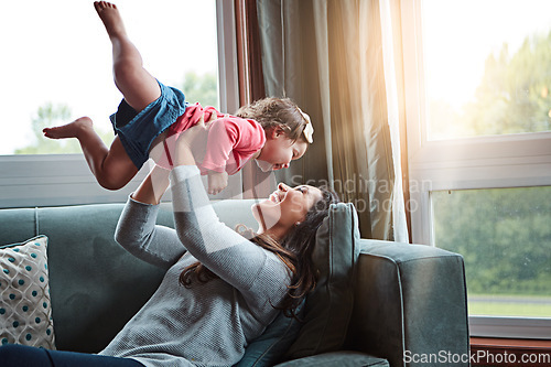 Image of Mom, happy and lifting girl on sofa in home living room and relax, bonding and quality time together or mother, love and family happiness. Child, mommy and playing game on couch in house with smile
