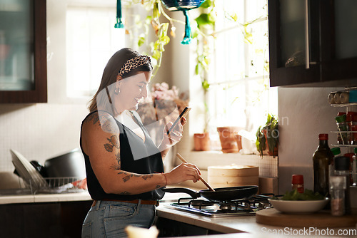 Image of Happy, woman cooking food with smartphone and in kitchen of a home. Dinner or lunch, multitasking and plus size, natural person with tattoo on cellphone following recipe motivation for healthy diet