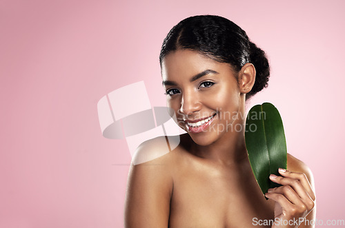 Image of Portrait, happy woman and leaf of skincare in studio, pink background and mockup of eco friendly cosmetics. Face, smile and african model for natural beauty, green plants and aesthetic sustainability