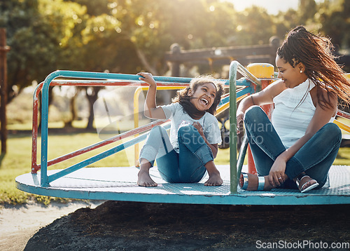 Image of Mother with daughter on roundabout at park, playing together with laughter and fun outdoor. Love, care and bonding with family happiness, woman and girl enjoying time at playground with freedom