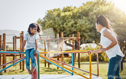 Image of Mom with daughter on roundabout at park, playing together with smile and fun outdoor. Love, care and bonding with happy family in nature, woman and girl enjoying time at playground with freedom