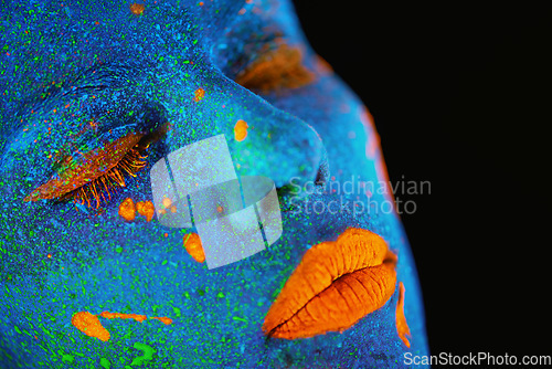 Image of Neon paint, makeup and woman face closeup with dark background and creative cosmetics. Surreal glow, fantasy and psychedelic cosmetic of a female model with unique and creativity art in studio