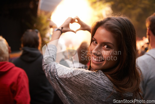 Image of Portrait, heart and hand gesture with a woman at a concert as part of the crowd or audience of a festival. Face, party and smile with a happy young female person outdoor at a music performance event