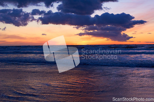 Image of Nature, ocean and peace with sunset at beach for landscape, summer break and vacation travel. Cloud, waves and environment with sunrise at coastline for sea holiday, calm horizon and seascape