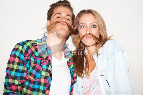 Image of Silly portrait of couple with hair moustache, funny face and gen z fashion with university culture in youth. Happiness, woman and hipster man in crazy picture at fun college event on wall background.