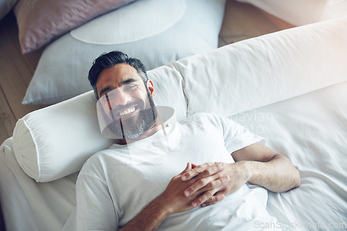 Image of Top view, portrait and man on his bed, relax and smile on a break, chilling and cheerful at home. Face, male person and happy guy in his bedroom, resting and wellness with joy, happiness and morning