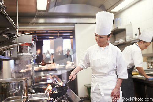 Image of Chef, woman and frying in restaurant kitchen, catering service and prepare food for fine dining. Professional, cooking and female person saute meat with cook pan making meal nutrition for hospitality