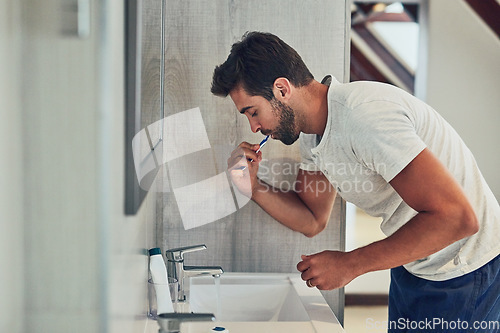 Image of Dental, sink and brushing teeth with man in bathroom for cleaning, morning routine or oral hygiene. Smile, cosmetics and health with male person and toothbrush at home for self care, breath or mouth