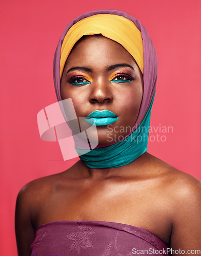 Image of Bold makeup, headwrap and portrait of a black woman isolated on a pink background in a studio. Bright, color and headshot of an African model with headwear and cosmetics for culture and lifestyle