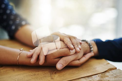 Image of Holding hands, support and closeup with trust, solidarity and community on a home table. Therapy, diversity and gratitude of friends together with hope, respect and love for grief empathy and forgive